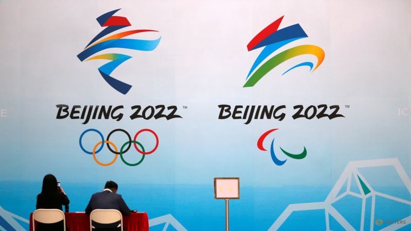 FILE PHOTO: Staff members sit near a board with signs of the 2022 Olympic Winter Games, at the National Aquatics Center, known colloquially as the "Ice Cube", in Beijing, China, Apr 1, 2021.