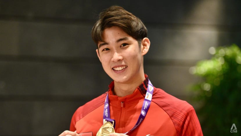 Loh Kean Yew poses with his medal during a press conference at Changi Airport on Dec 21, 2021. (Photo: Jeremy Long)